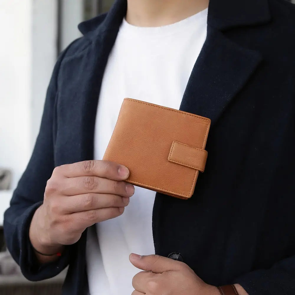 Person holding a cognac leather wallet with a blurred background