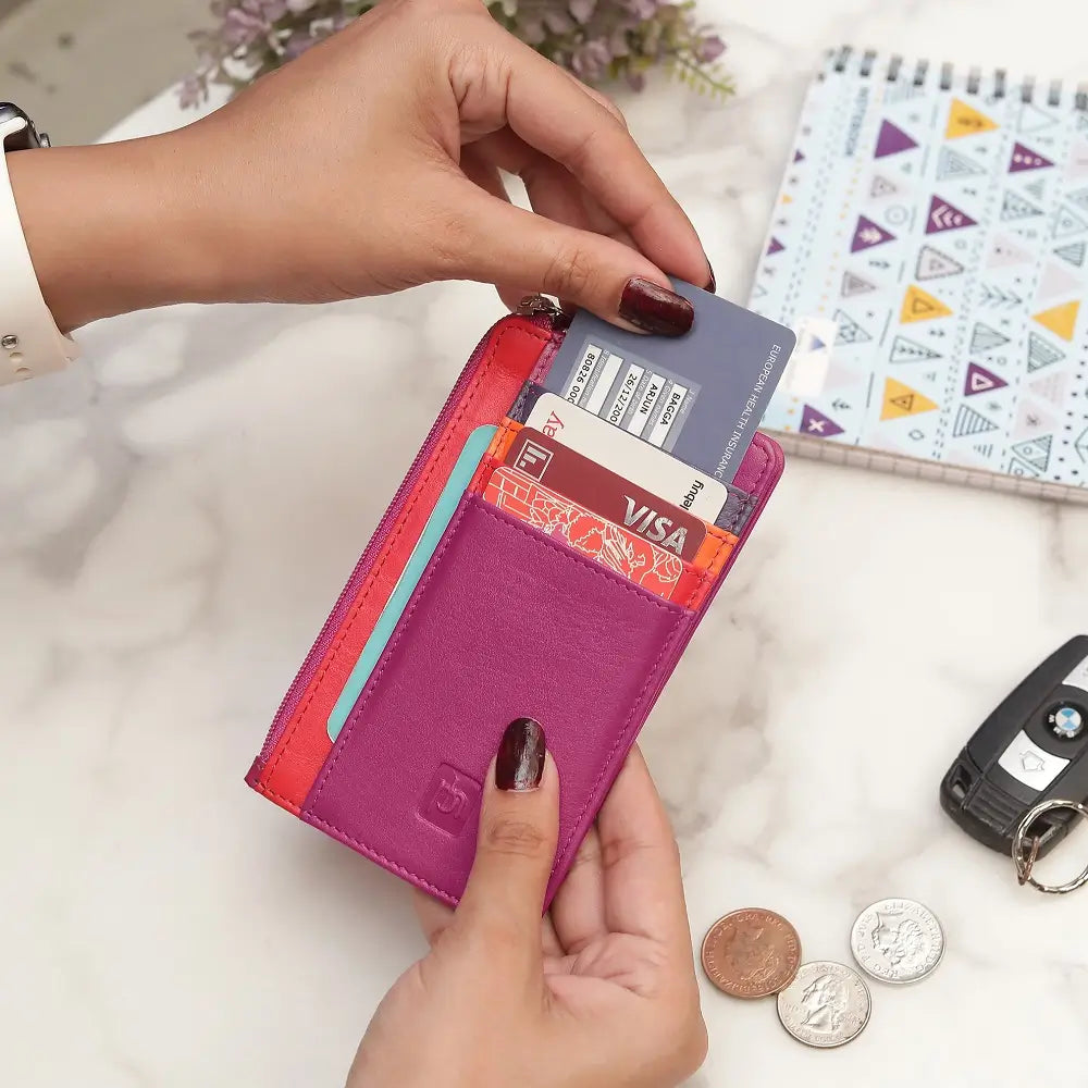 Person holding a Fuchsia Card Holder Purse with cards and coins on a light surface with a notebook and car key.