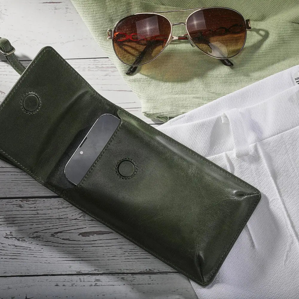 Green leather wallet with sunglasses on a wooden surface