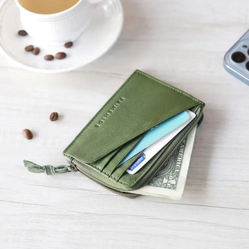 Green wallet with money and a  on a white surface with coffee and beans.