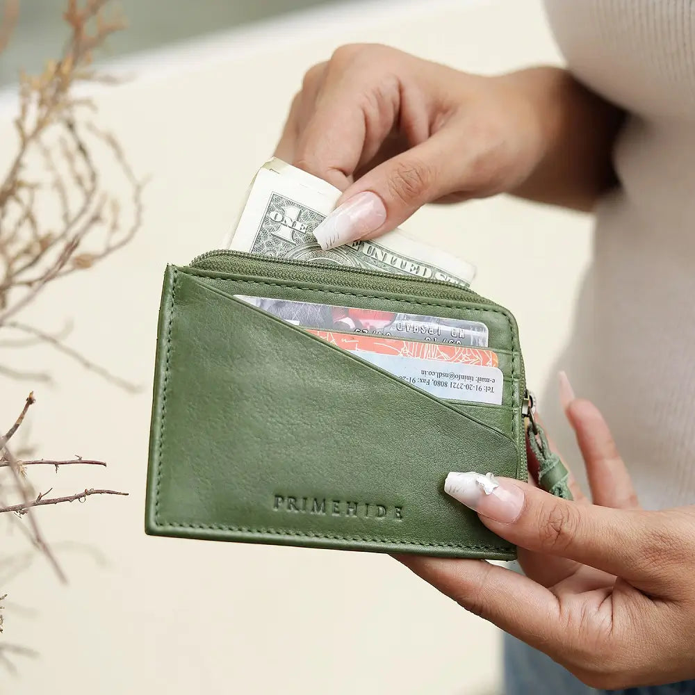 Green wallet with money held by a person's hand on a light background