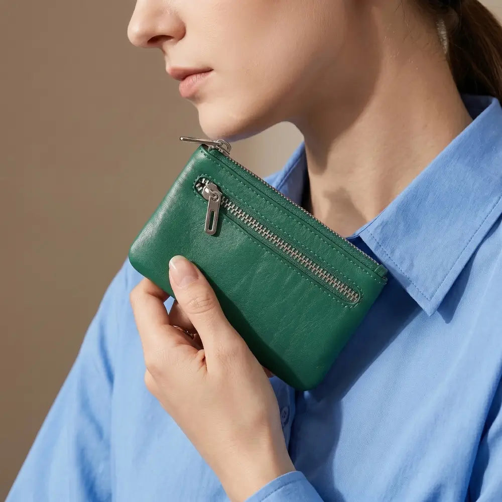 Person holding a green wallet against a neutral background
