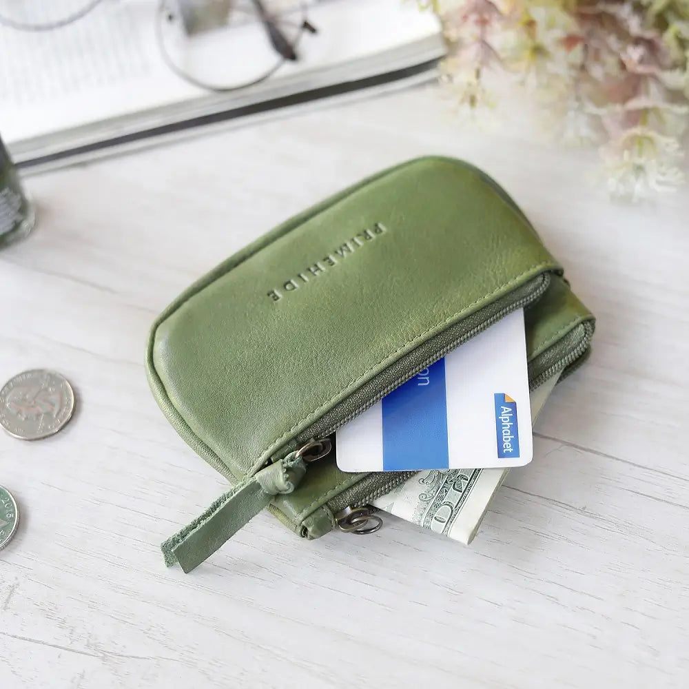 Green wallet with coins and cards on a light surface