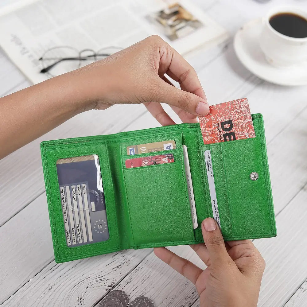 Green wallet with cards on a wooden surface with a cup of coffee in the background