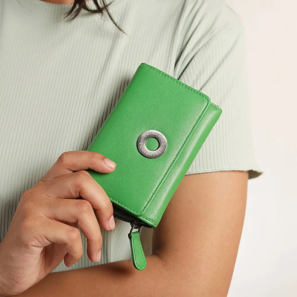 Green wallet with a metallic ring detail held by a person against a neutral background