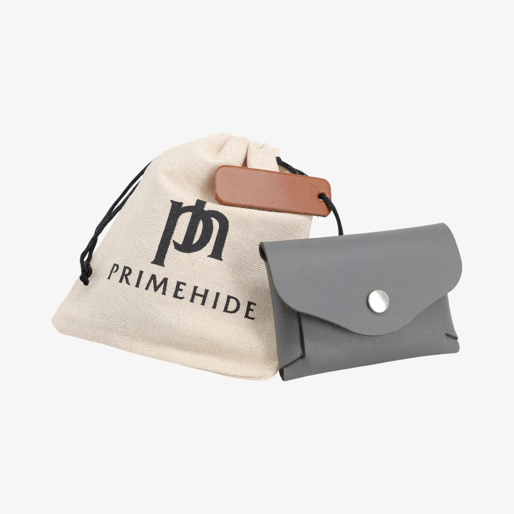 Grey leather coin purse with flap closed displayed beside Primehide dust bag