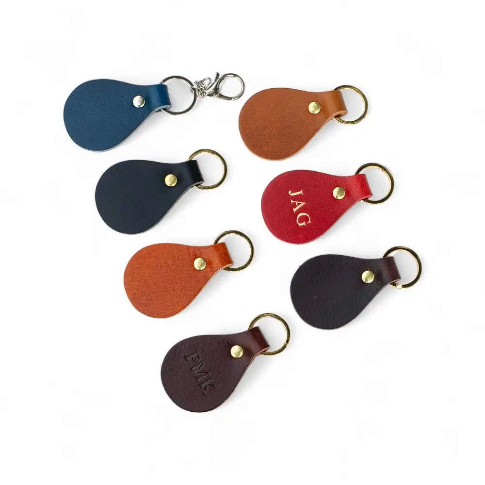 Set of leather keychains in various colors with initials engraved on a white background