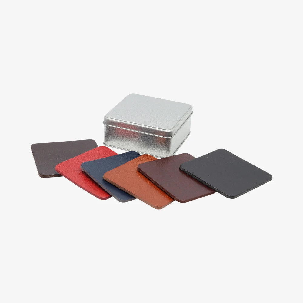Set of color Full grain leather coasters gift for home in various shades with a metal tin on a white background