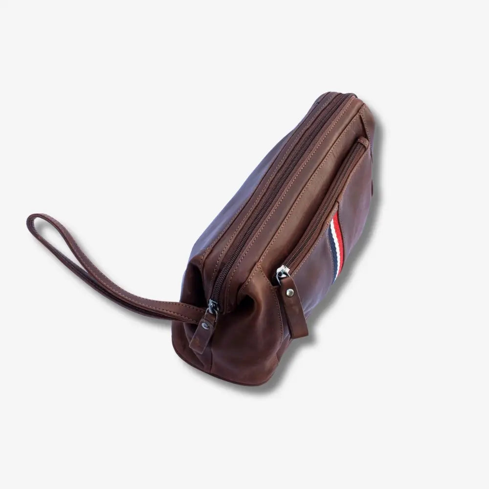 A tan leather wristlet pouch with a wrist strap, shown from an angled top-down view on a light gray background.