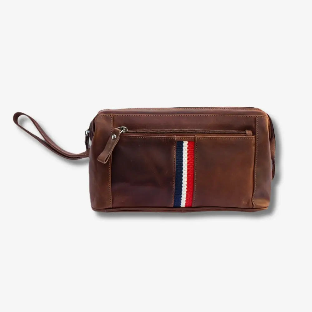 A tan leather washbag  with a vertical red, white, and blue striped accent on the front pocket, shown on a light gray background.