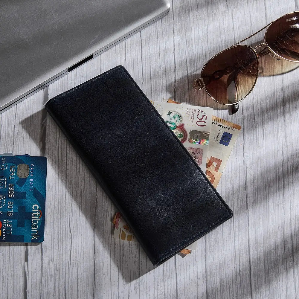 Navy wallet with sunglasses, money, and a card on a wooden surface