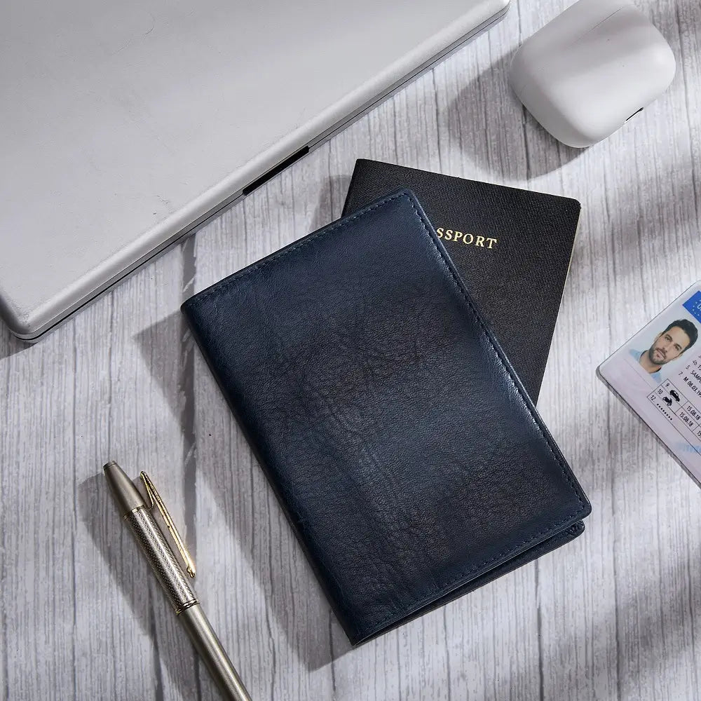 Navy leather passport holder with a passport and ID card on a wooden surface.
