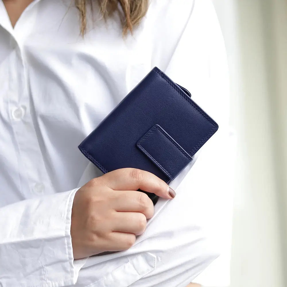 Person holding soft navyleather trifold purse with secure tab fastening