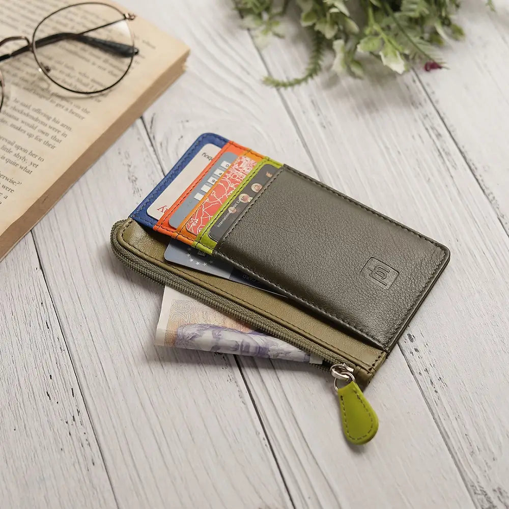 Olive Leather cardholder purse  with green zipper on a wooden surface with a book and glasses.