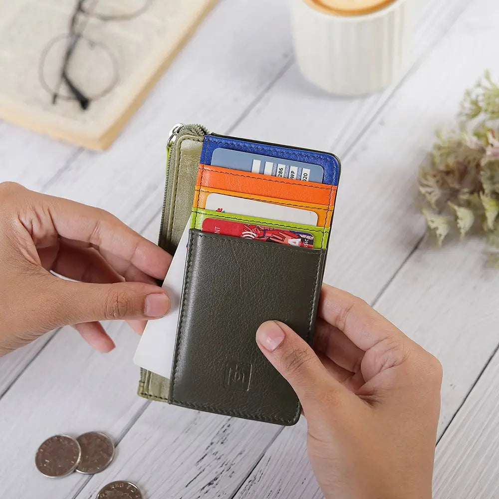 Person holding a Olive Leather cardholder purse  with colorful card slots on a wooden surface.