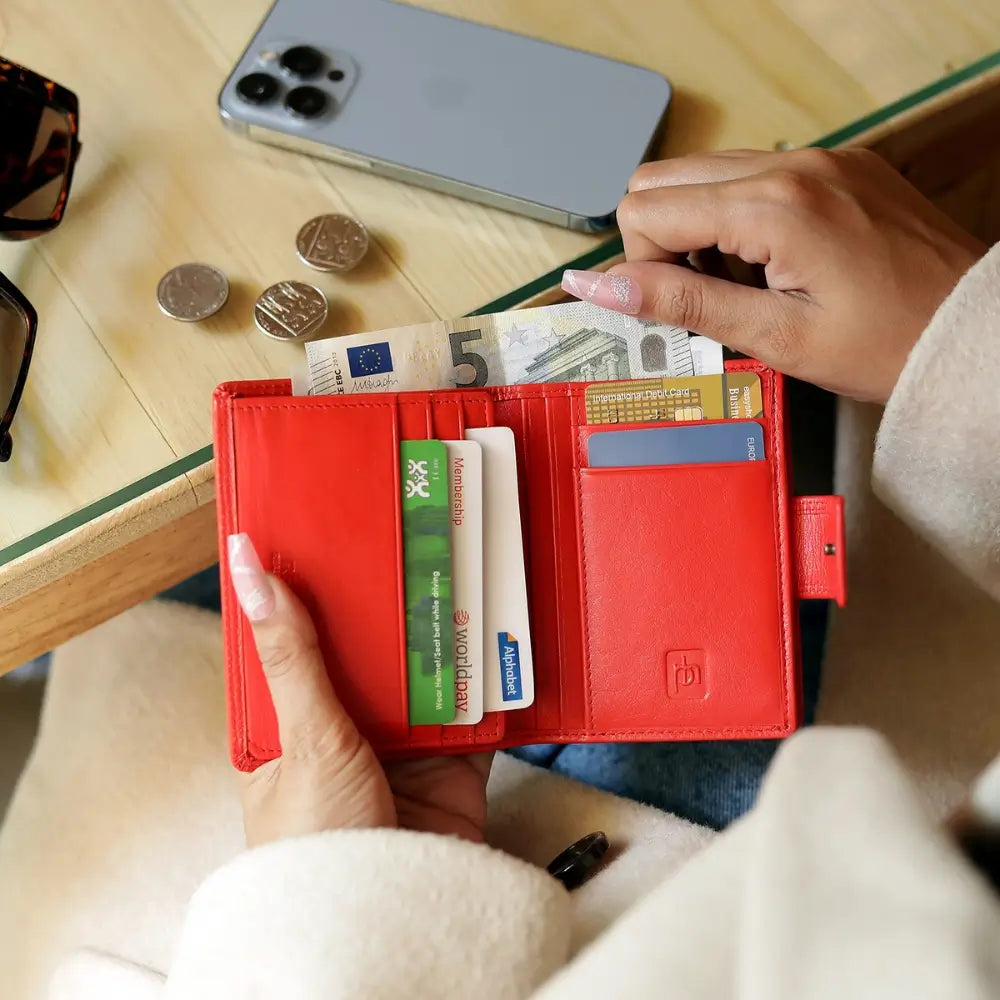 Person holding soft orange leather trifold purse with secure tab fastening