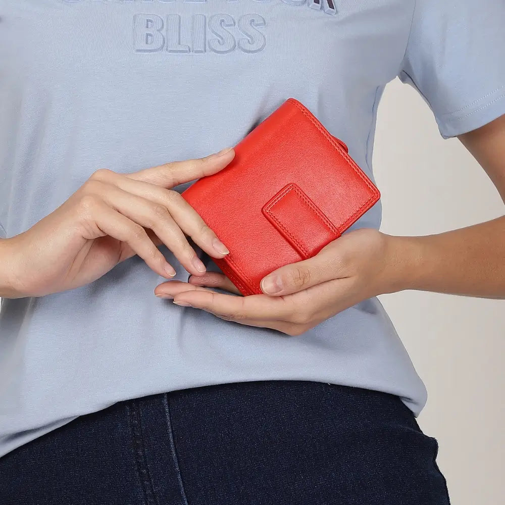 Person holding soft orange leather trifold purse with secure tab fastening