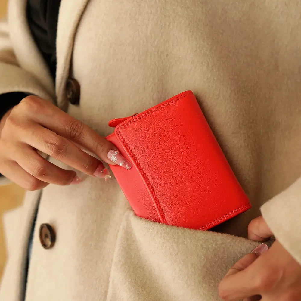 Orange wallet being placed into a beige coat pocket