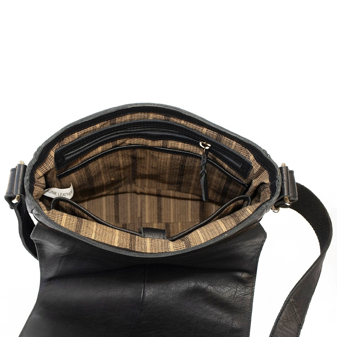 a messenger bag is open to show a fabric lined interior with a zipped pocket