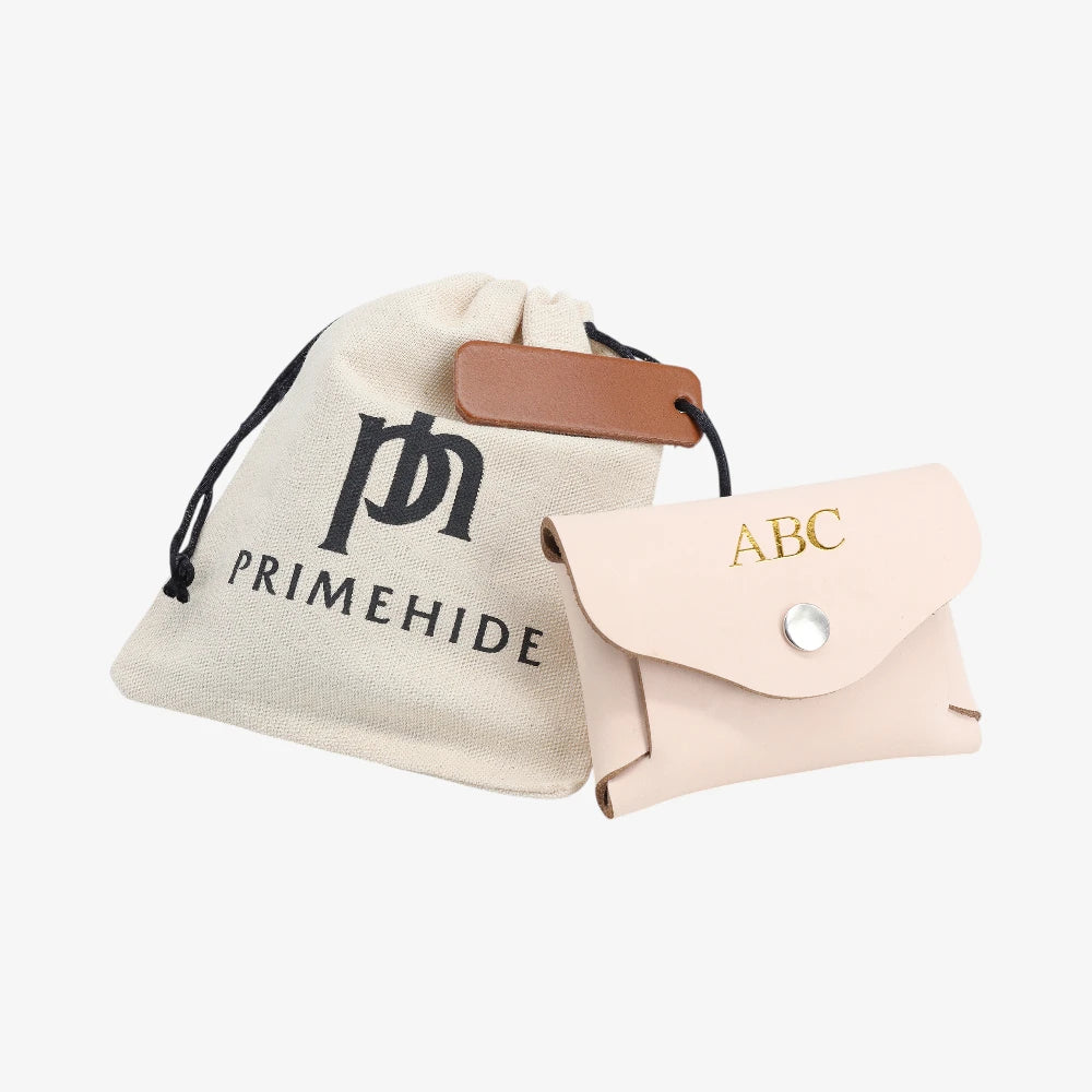 Peach leather coin purse with flap closed displayed beside Primehide dust bag