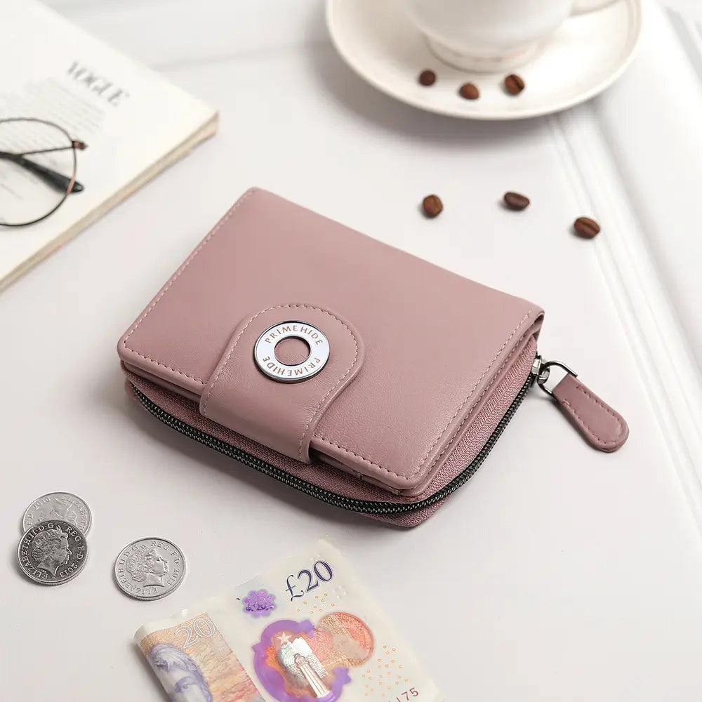 Pink wallet with a button on a white surface with coins and money.