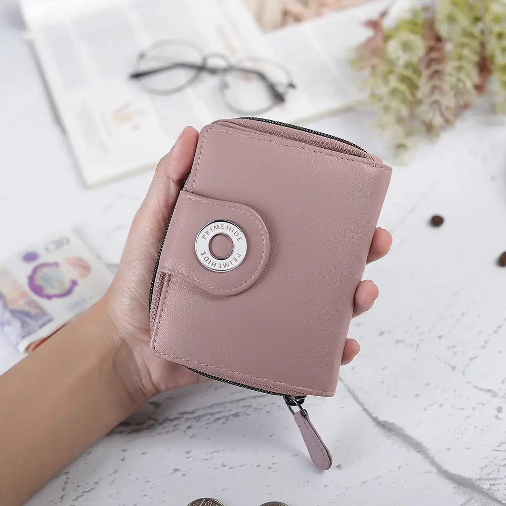 Hand holding a pink wallet with a decorative button on a light surface.