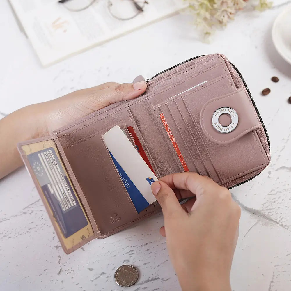 Person opening a pink wallet to reveal cards and coins on a light surface.