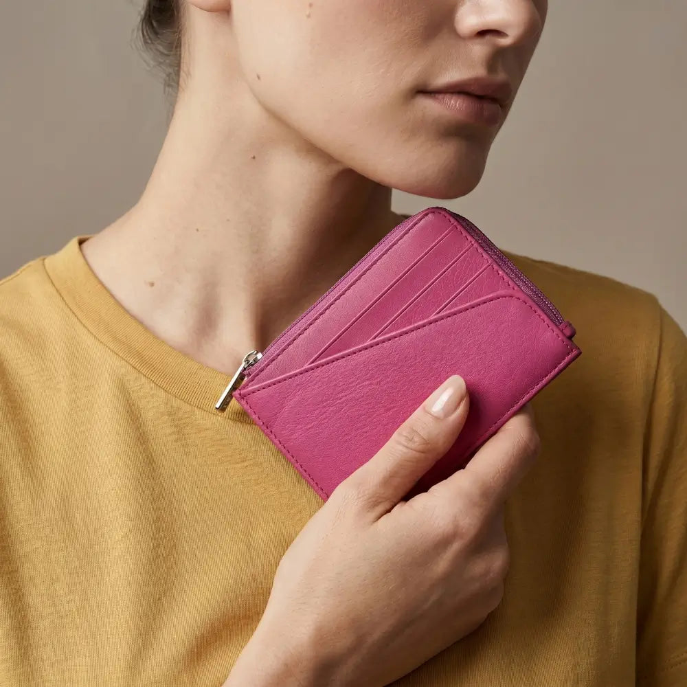 Person holding a pink wallet against a neutral background