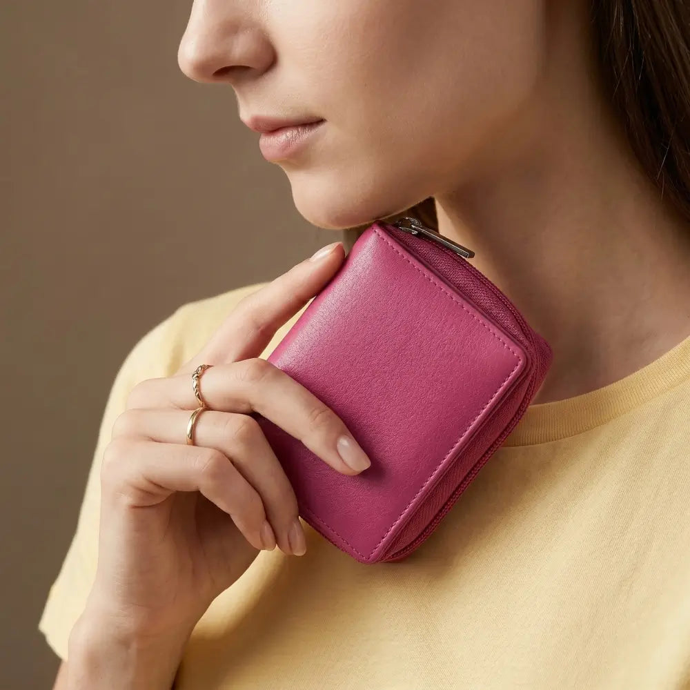 Person holding a pink wallet against a neutral background