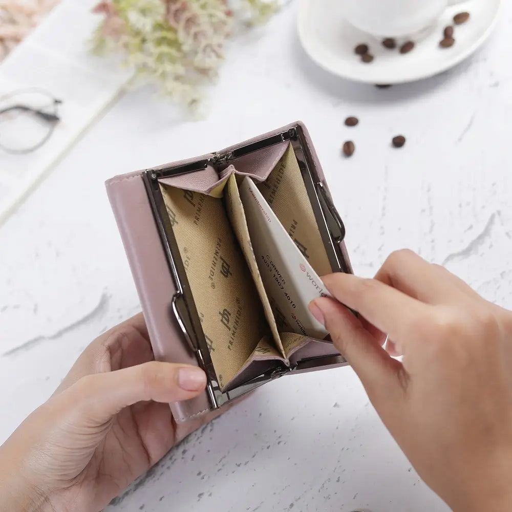 Person opening a pink cardholder with compartments on a light surface.