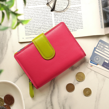 Pink purse with green strap on a marble surface with coins and cards