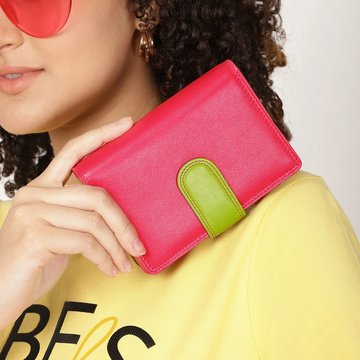 Person holding a pink wallet with a green strap against a neutral background