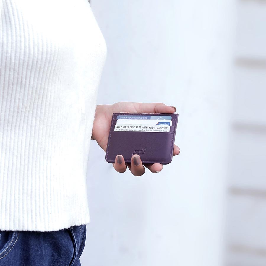 Person holding a purple leather card holder filled with cards