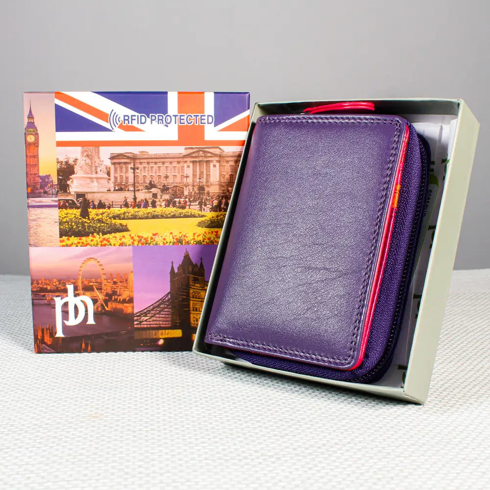 A purple RFID-protected leather wallet shown partially inside its open presentation box, with the printed outer box standing beside it on a light gray surface.