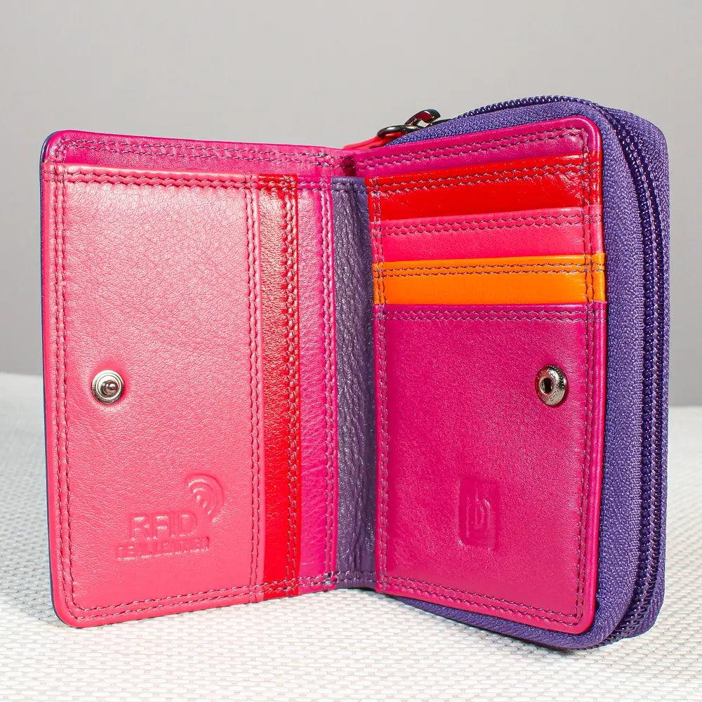 An open bifold wallet in textured leather, showing a vibrant pink interior with card slots, a bright orange accent stripe, and a purple exterior zipper.