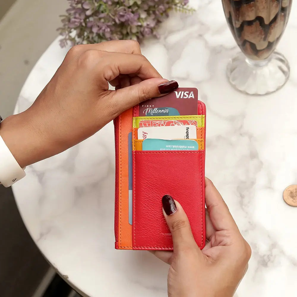 Red Card Holder Purse  with multiple cards being held by a person on a marble surface.
