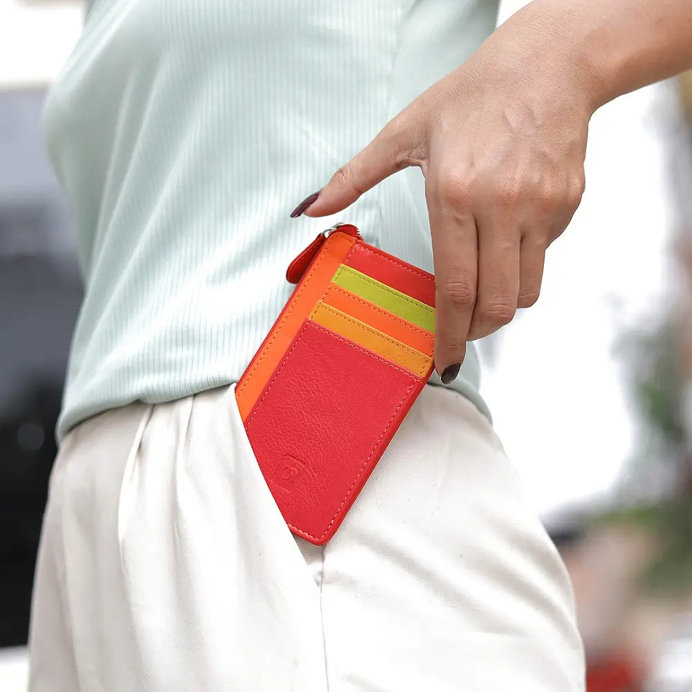 Person holding a red cardholder with colorful slots against a blurred background