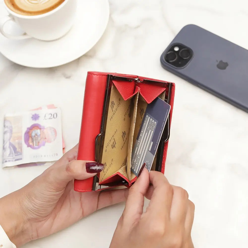 Red wallet with cards, a phone, and a cup of coffee on a white surface