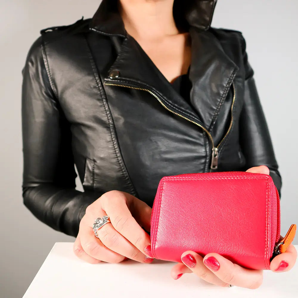Person holding a red wallet with a plain background