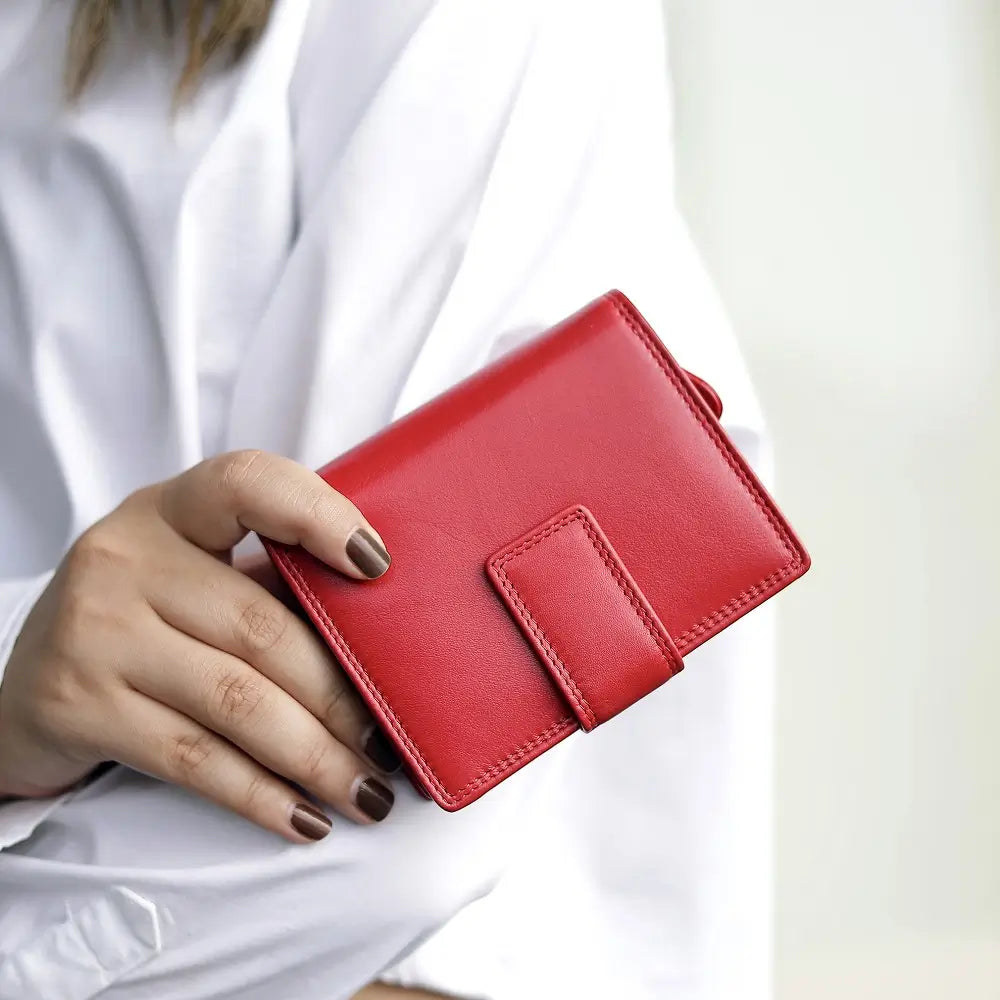 Person holding soft red leather trifold purse with secure tab fastening