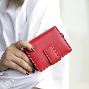 Person holding soft red leather trifold purse with secure tab fastening
