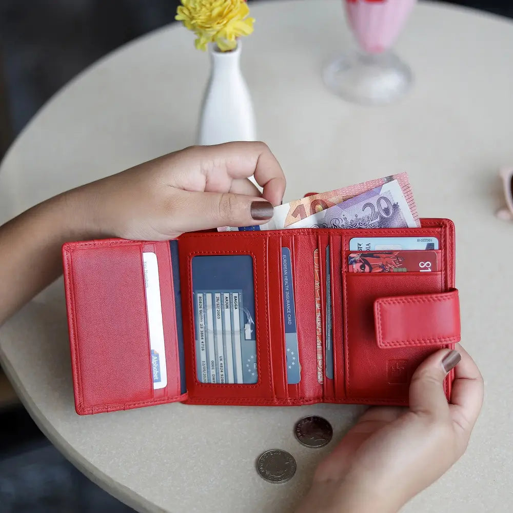 Person holding soft redleather trifold purse with secure tab fastening