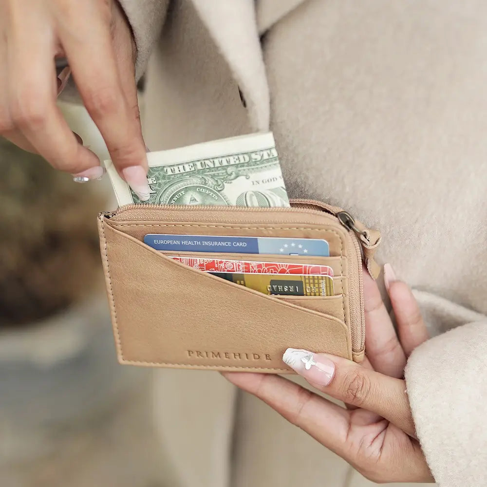 Person holding a Sand wallet with money and cards, wearing a beige coat.