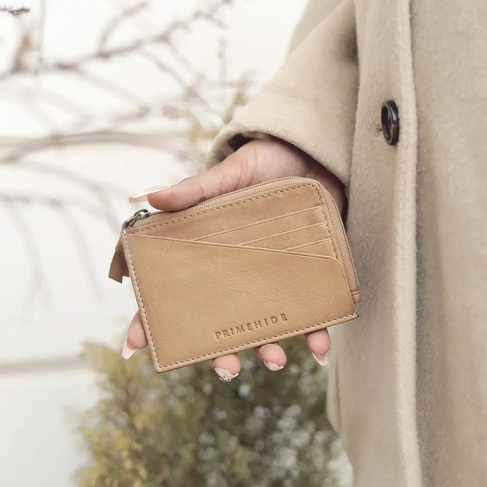 Person holding a Sand leather wallet with 'PRIMEHIDE' branding outdoors.