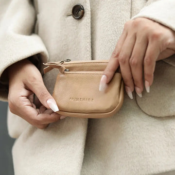 Person holding a small Sand purse with 'FREYRS' branding against a neutral background.