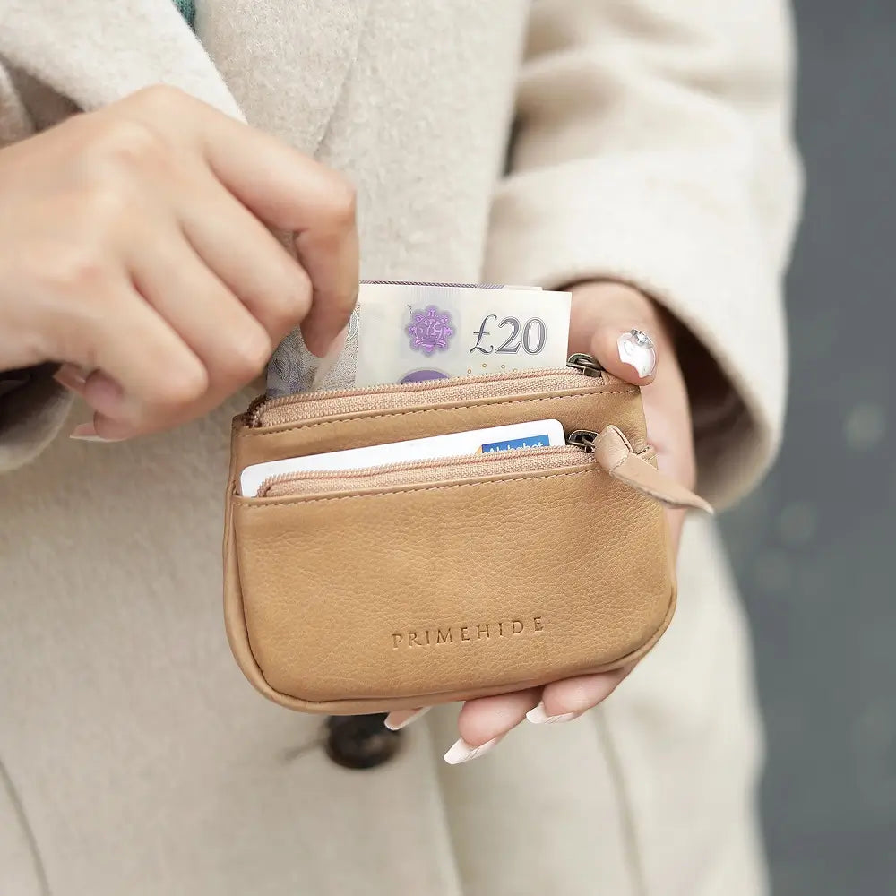 Person holding a Sand wallet with money and cards, wearing a beige coat.