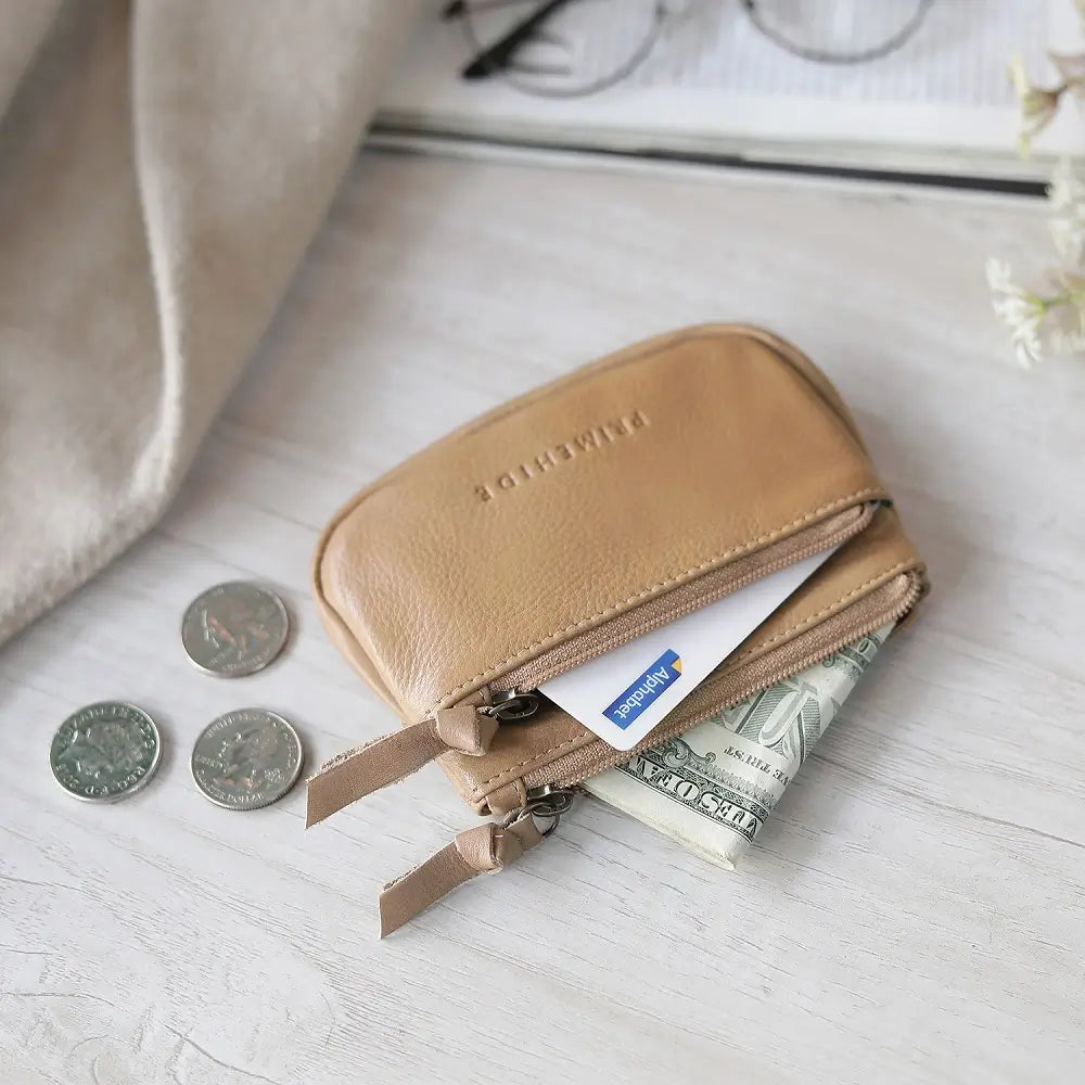 Sand leather wallet with coins and money on a light wooden surface