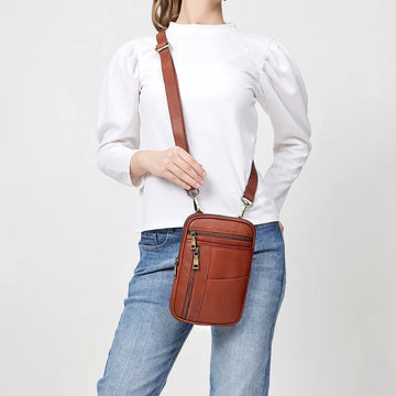 A tan leather crossbody bag with adjustable straps and Brass hardware.