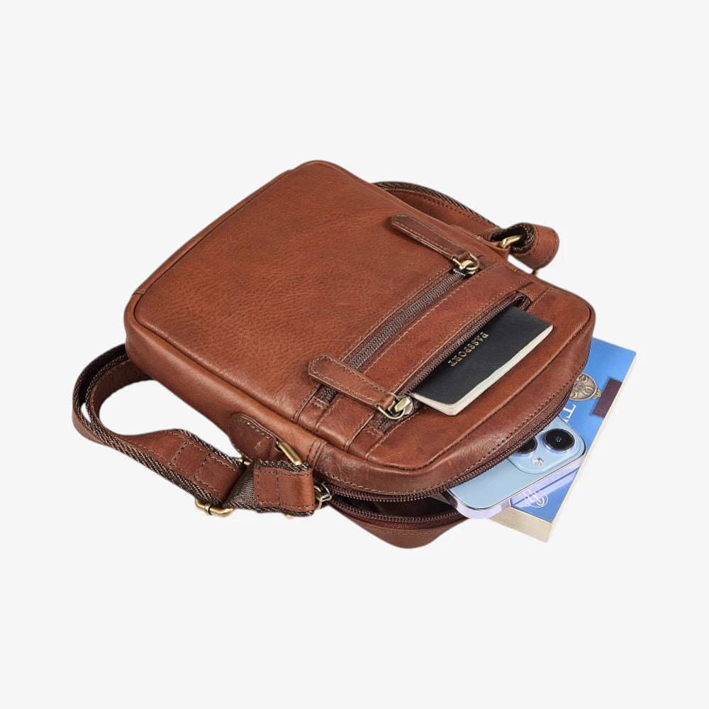 Brown leather crossbody bag with a phone and wallet on a white background