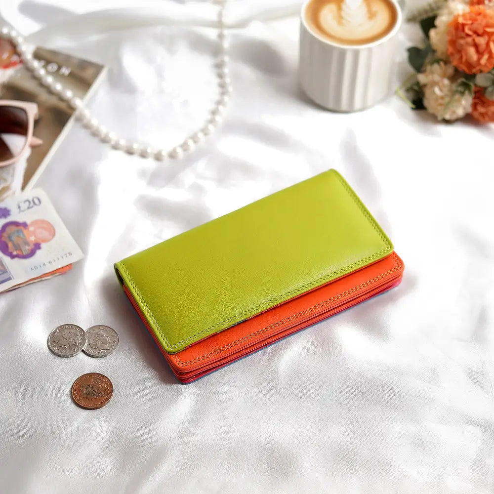 Green wallet on a textured surface with coins and a banknote.